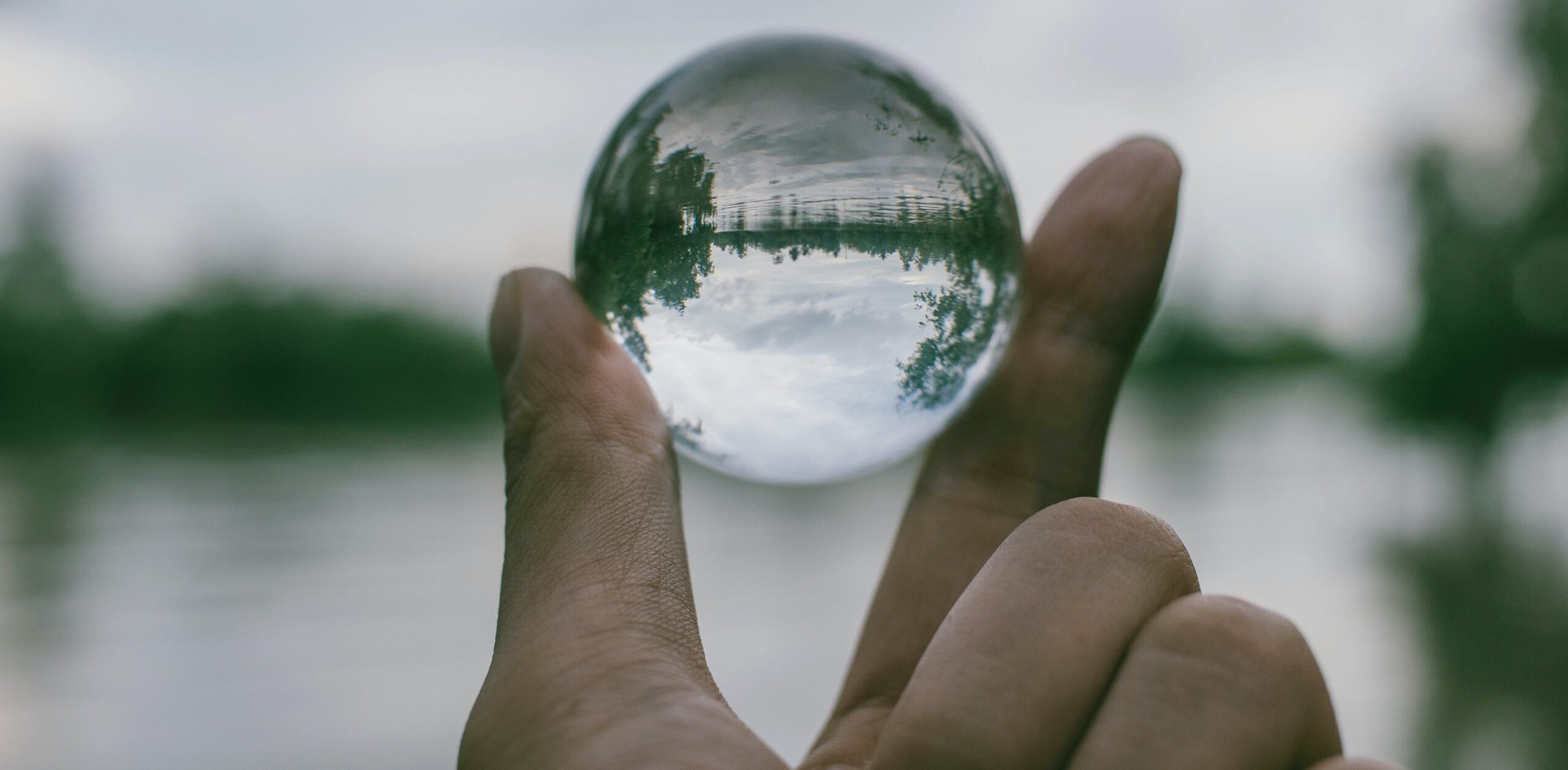 view of a lake and trees through a glass sphere